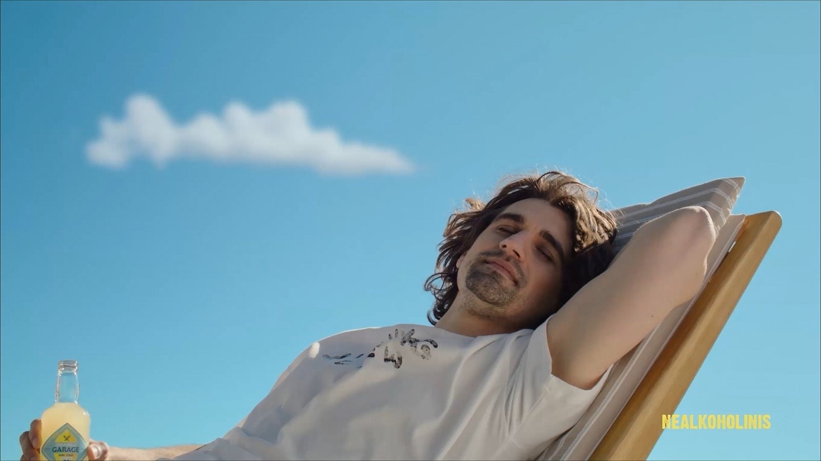 Seth & Riley's Garage Hard Lemon commercial – man relaxing on a sun lounger against a blue summer sky